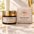 Crema viso Le Perle Hebe Aura Skin in vasetto scuro con coperchio dorato, accanto alla scatola color crema con dettagli dorati.